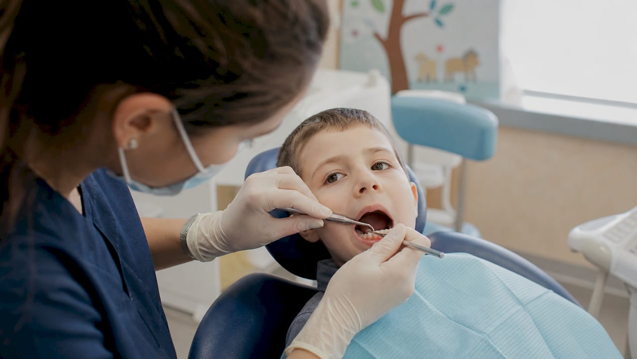 Dentist fitting fixed space maintainer in child's mouth