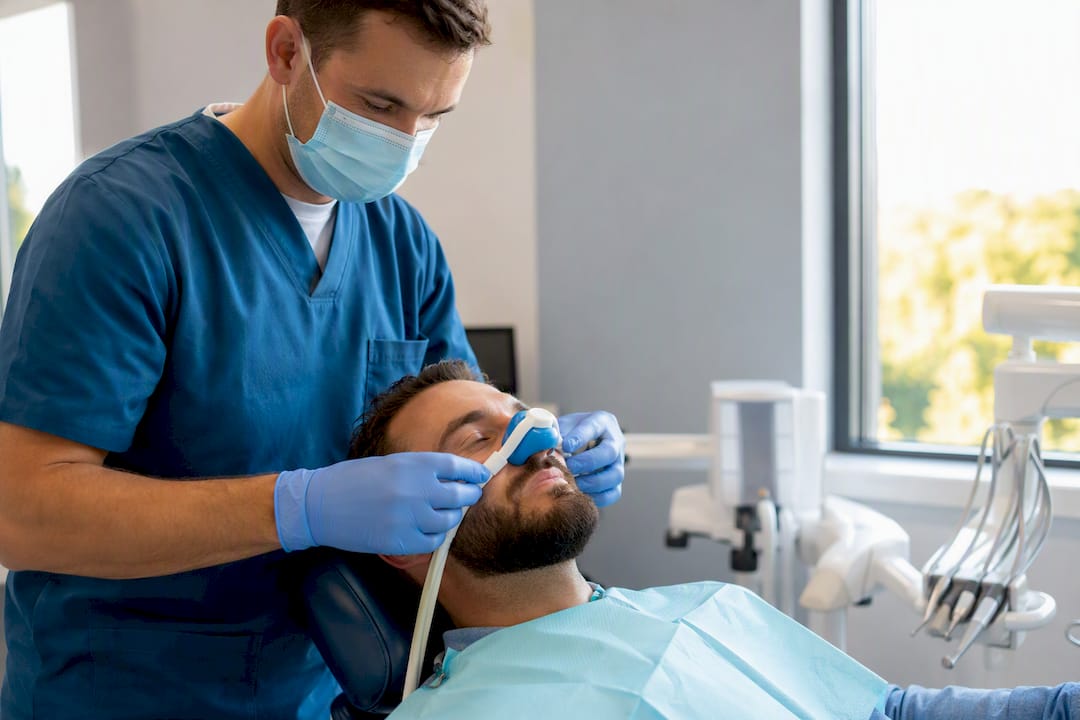 Dentist placing nitrous oxide nasal hood on patient