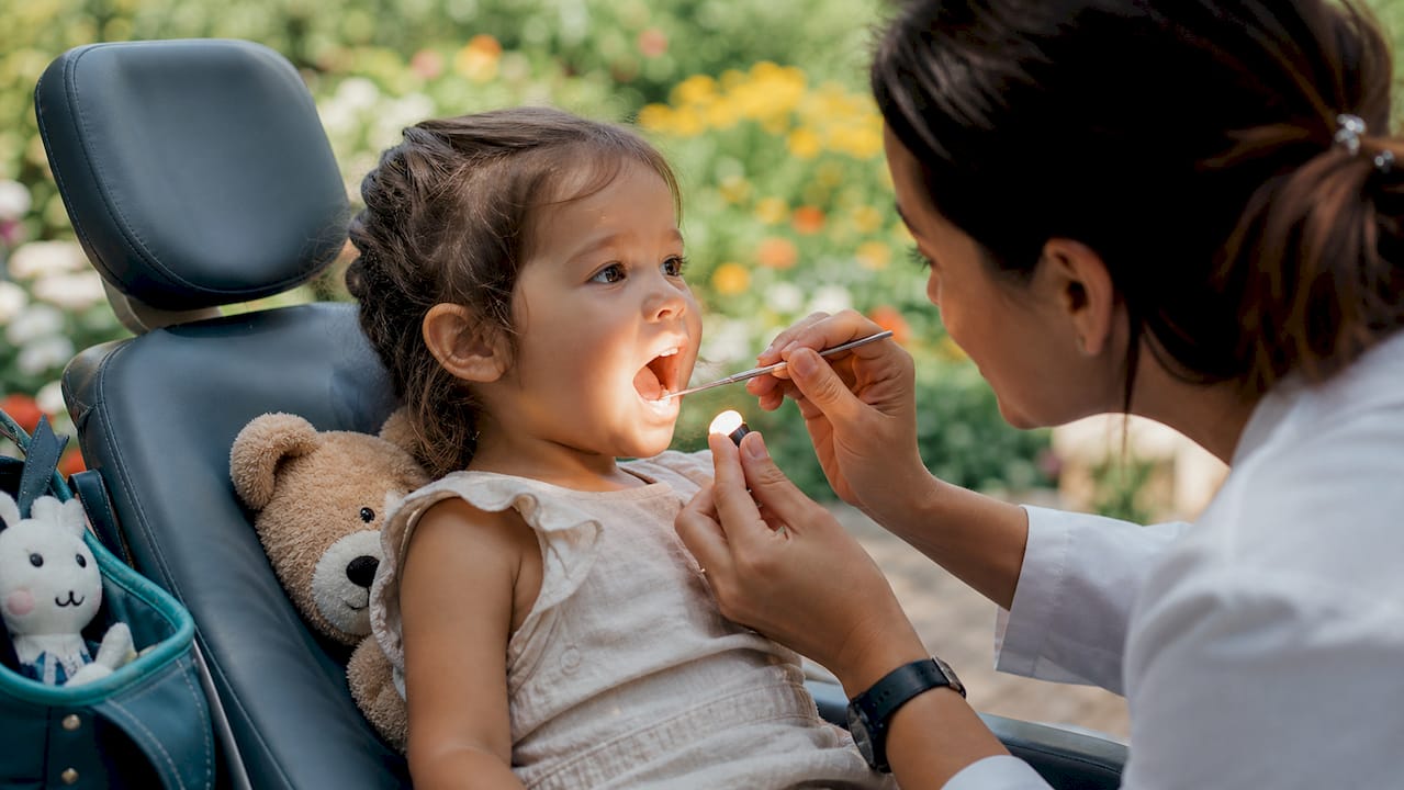 Dentist inspecting toddler's teeth in pediatric room