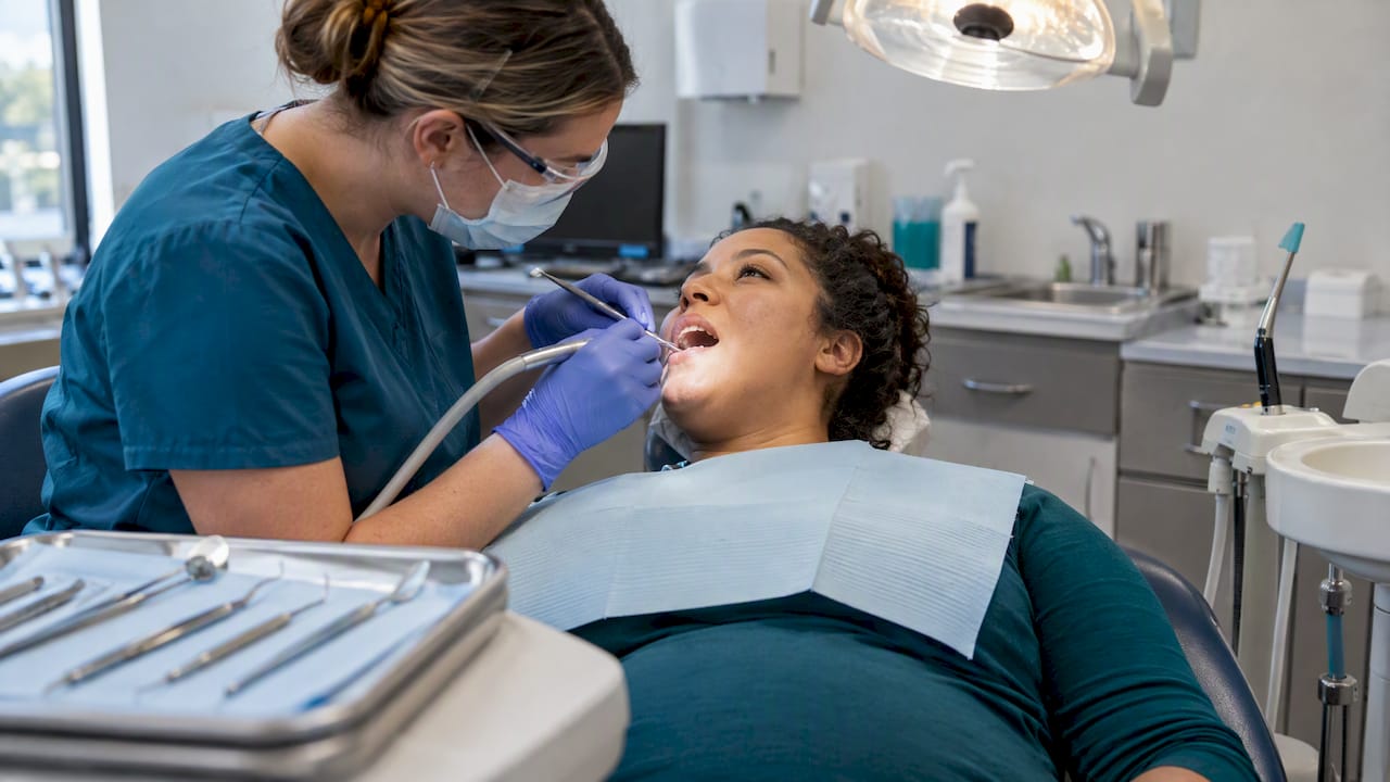Hygienist cleaning a pregnant patient's teeth