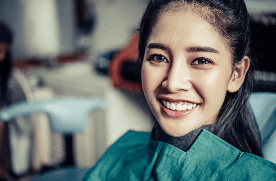 Smiling female patient during a Cosmetic Dentistry visit, showing healthy and bright teeth.